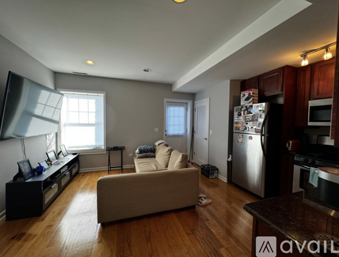 A living room with a couch, a television, and a kitchen area with a refrigerator and oven.