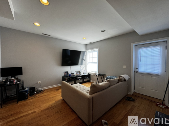 A living room with a couch, television, and a window with blinds.
