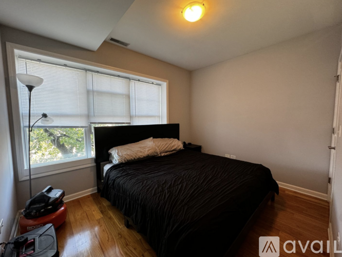 A bedroom with a black bed and a window with blinds.