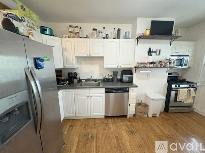 A kitchen with white cabinets and a wooden floor.