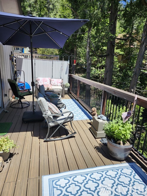 A deck with a blue umbrella and a pool.
