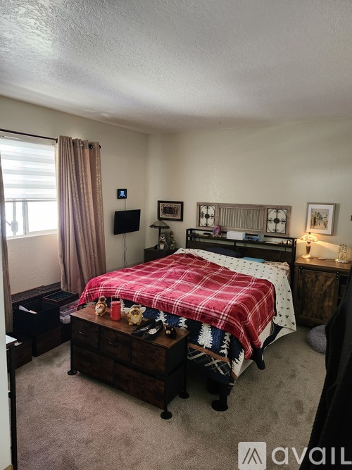 A bedroom with a bed, nightstand, and window.