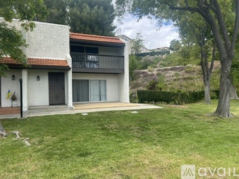 A house with a balcony and a green lawn in front.