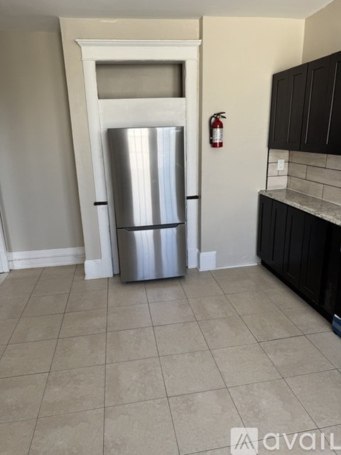 A silver refrigerator in a kitchen with black cabinets.