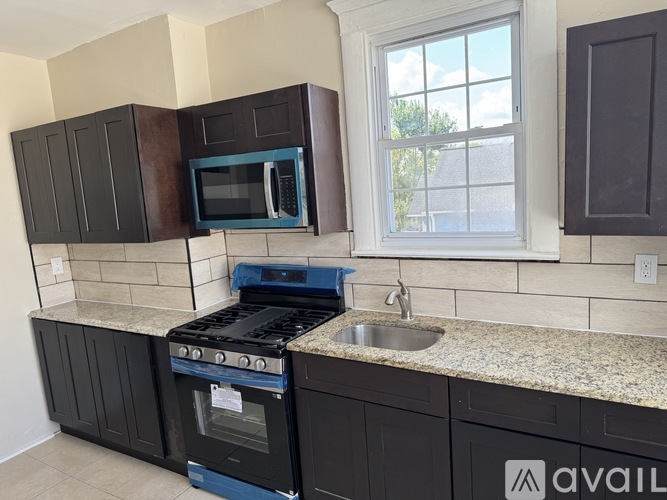A kitchen with black cabinets and a granite countertop.
