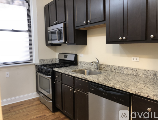 A kitchen with black cabinets and a granite countertop.