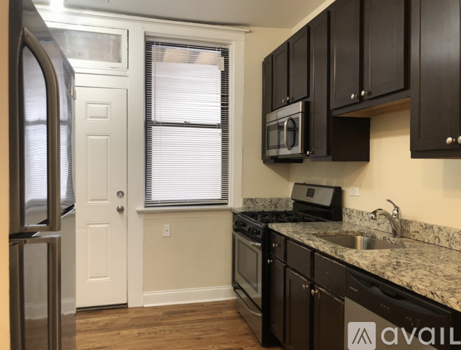 A kitchen with a granite countertop and black cabinets.