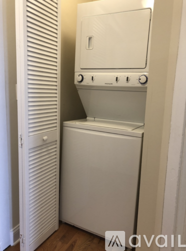 A white dishwasher is in a narrow space between a wall and a cabinet.