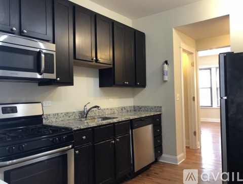 A kitchen with black cabinets and a granite countertop.