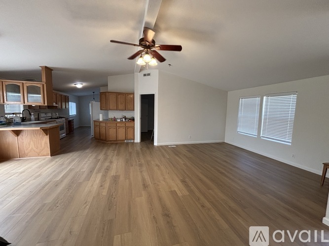 A spacious room with wooden flooring and a ceiling fan.
