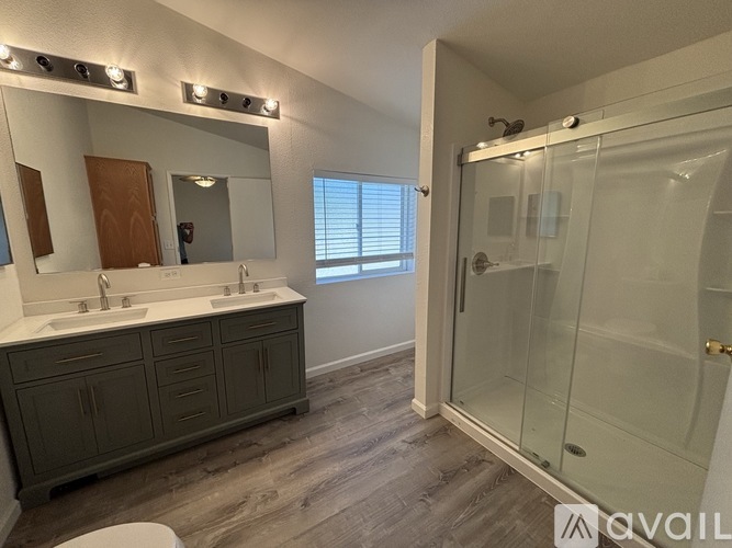 A bathroom with a sink, mirror, and shower.
