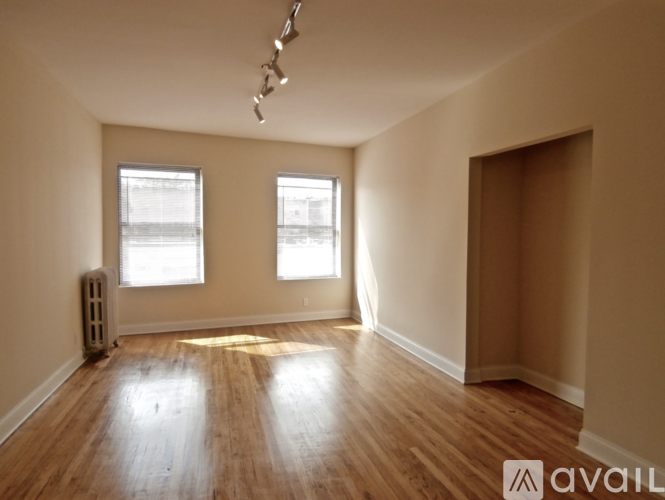 A room with wooden floors and two windows.