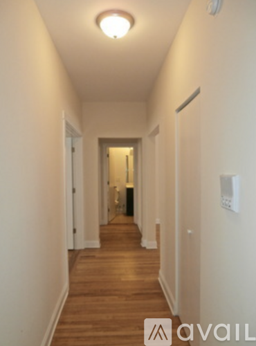 A long hallway with a light on the ceiling and a door at the end.