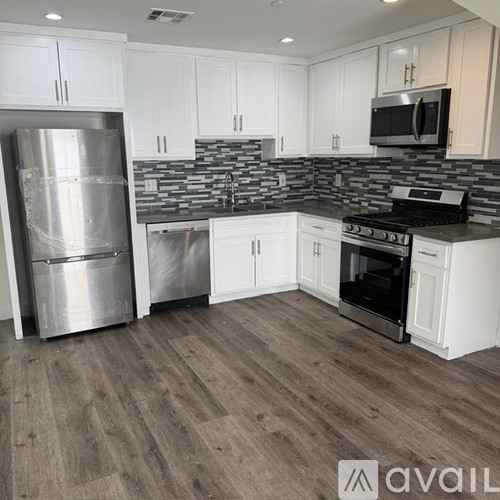 A kitchen with white cabinets and a stainless steel refrigerator.