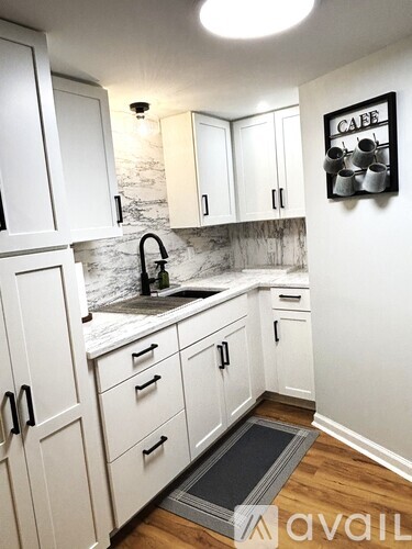 A kitchen with white cabinets and a marble backsplash.