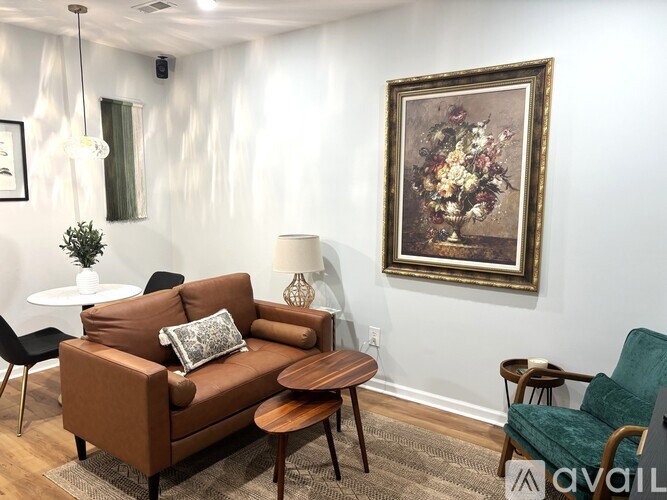 A living room with a brown couch, a green chair, and a painting on the wall.