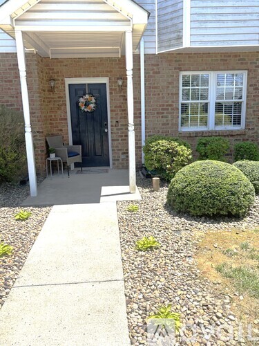 A house entrance with a black door and a wreath on it.