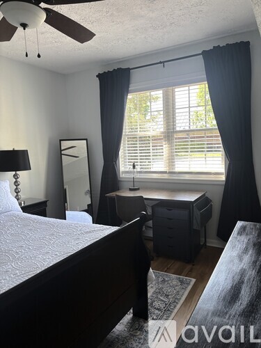 A bedroom with a bed, dresser, and window with blinds.
