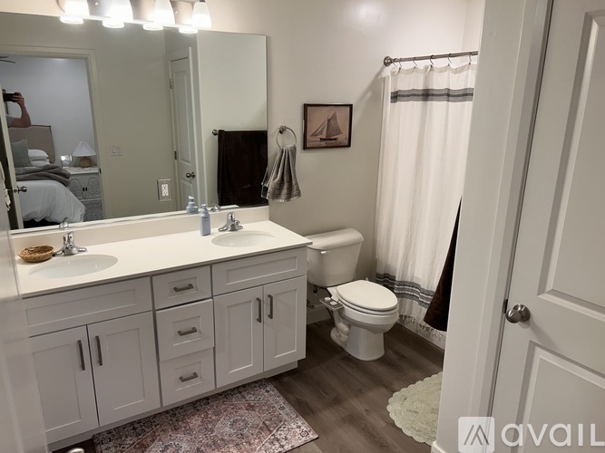 A bathroom with a white sink, toilet, and cabinets.