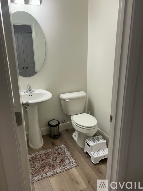 A bathroom with a toilet, sink, and mirror.