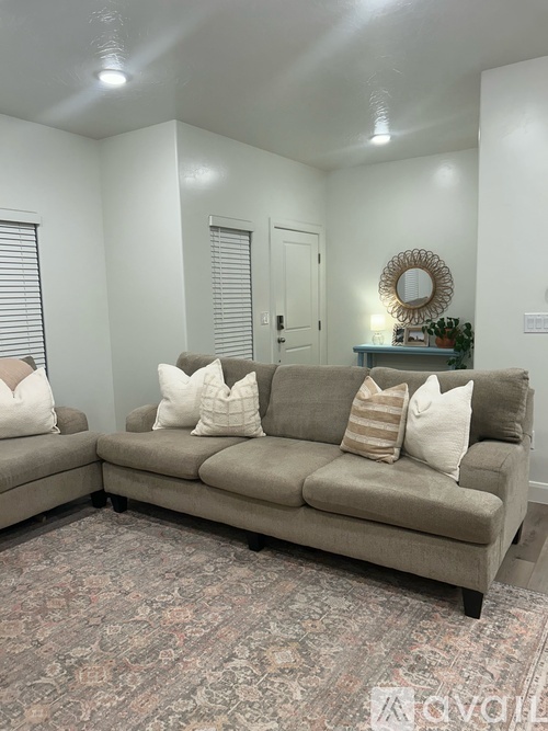 A living room with a grey couch and a patterned carpet.