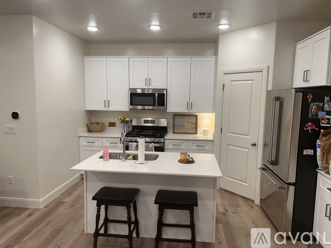 A kitchen with white cabinets and a black fridge.