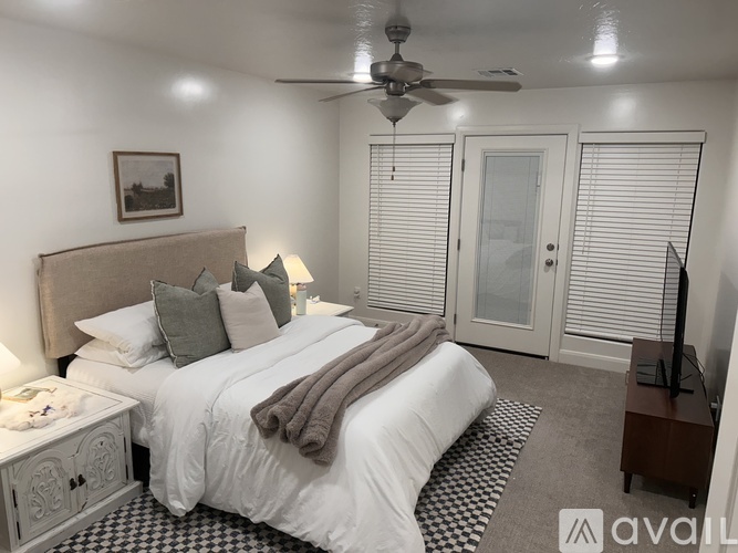 A bedroom with a large bed, a ceiling fan, and a picture on the wall.