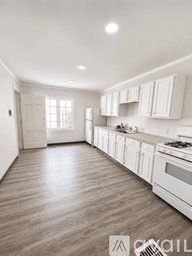 A kitchen with white cabinets and a wooden floor.