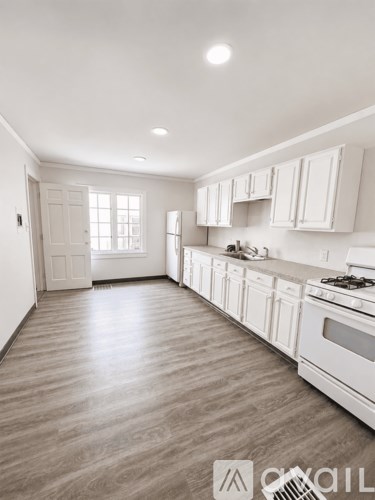 A kitchen with white cabinets and a wooden floor.
