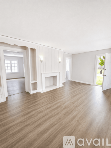 A room with wooden flooring and white walls.