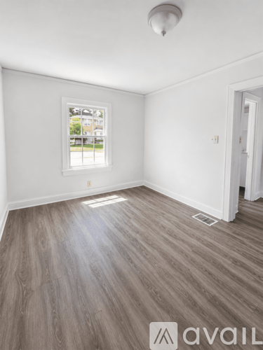 A room with wooden flooring and a window showing a view of a street.