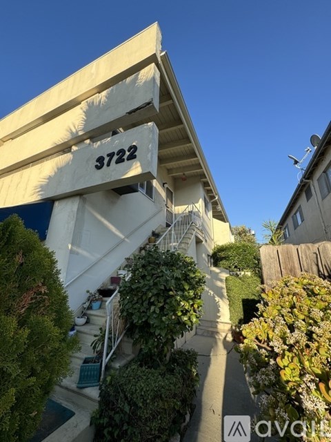 A house numbered 3722 with a white facade and a staircase leading to the entrance.