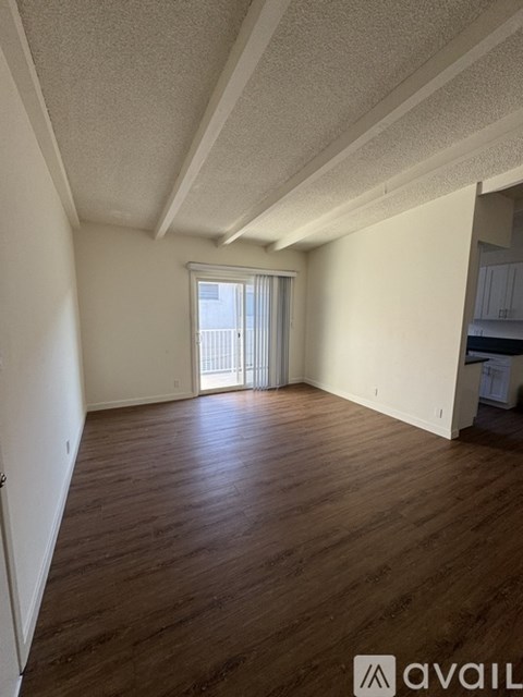 A room with wooden floors and a window with blinds.