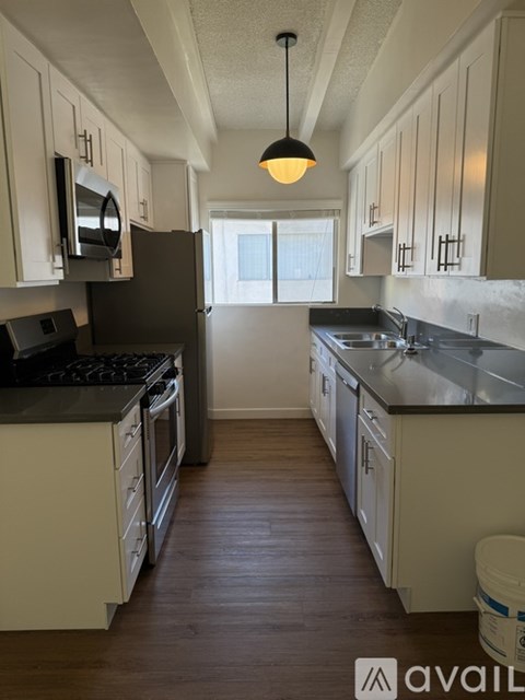 A kitchen with white cabinets and black countertops.