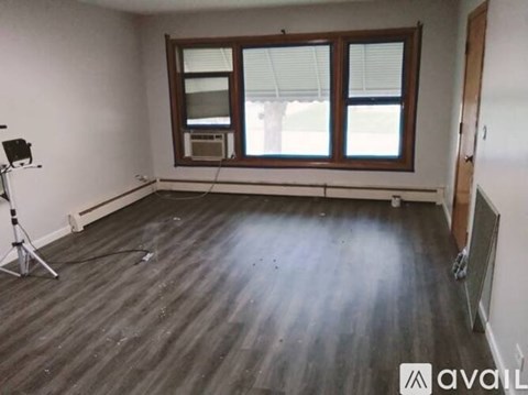 A room with wooden flooring and a window with blinds.