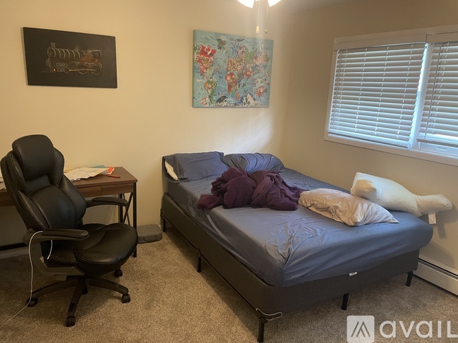 A bedroom with a bed, desk, chair, and two pictures on the wall.