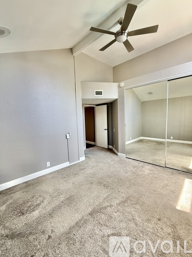 A spacious room with a ceiling fan and a carpeted floor.