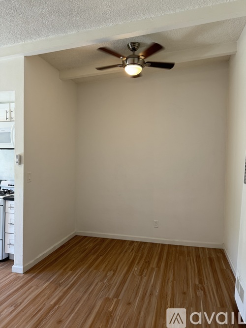 A room with a ceiling fan and wooden flooring.