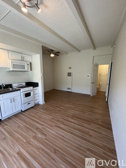 A kitchen with white cabinets and a wooden floor.
