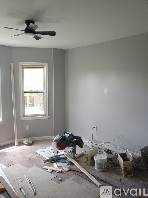 A room with a ceiling fan and a window under construction.