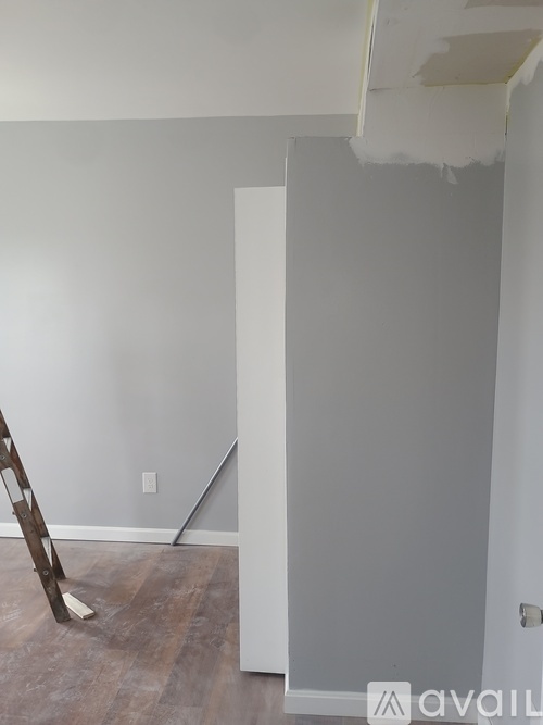 A room with a ladder and a wall with a hole in it.