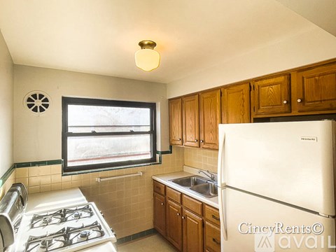 A kitchen with a white fridge, a stove with four burners, and wooden cabinets.
