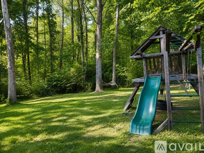 A playground with a green slide in a sunny park.