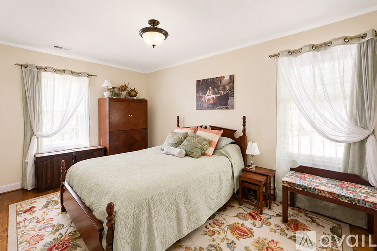 A bedroom with a large bed and a wooden dresser.