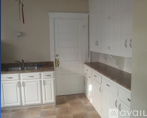 A kitchen with white cabinets and a white door.