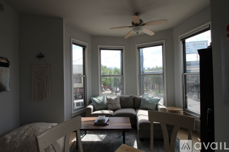 A living room with a couch, chairs, and a ceiling fan.