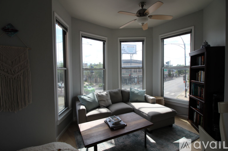 A living room with a couch, a table, and a fan.