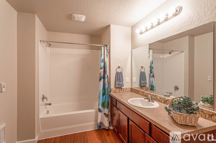 A bathroom with a white tub, sink, and a mirror.