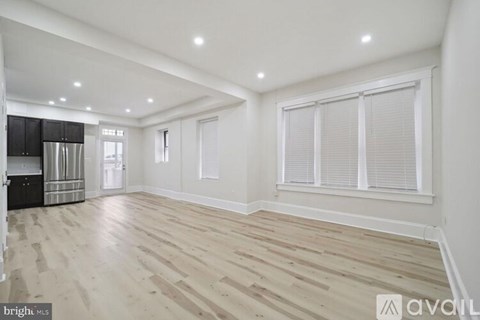 A spacious room with wooden flooring and white walls.