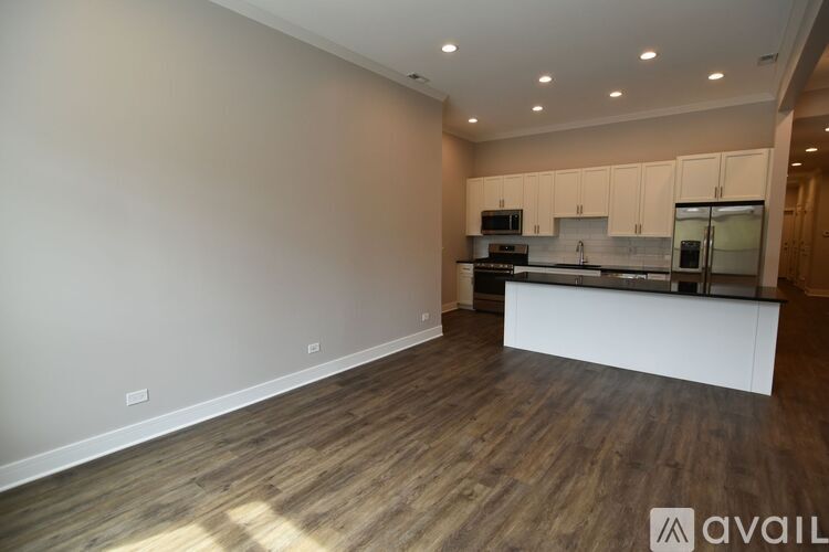 A spacious kitchen with wooden flooring and white cabinets.